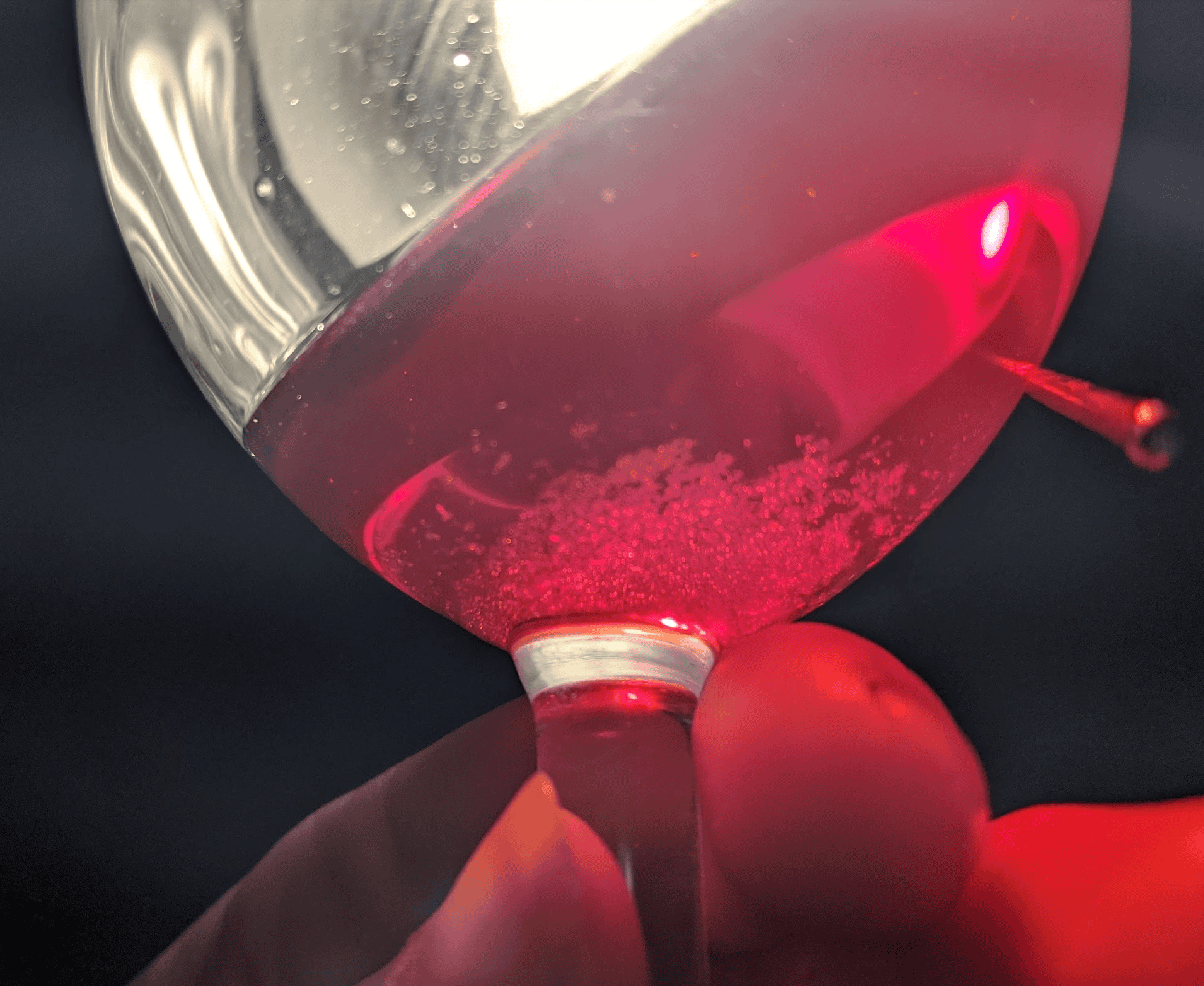 Fine tartrate crystal sediment settling at the bottom of a glass of rose wine