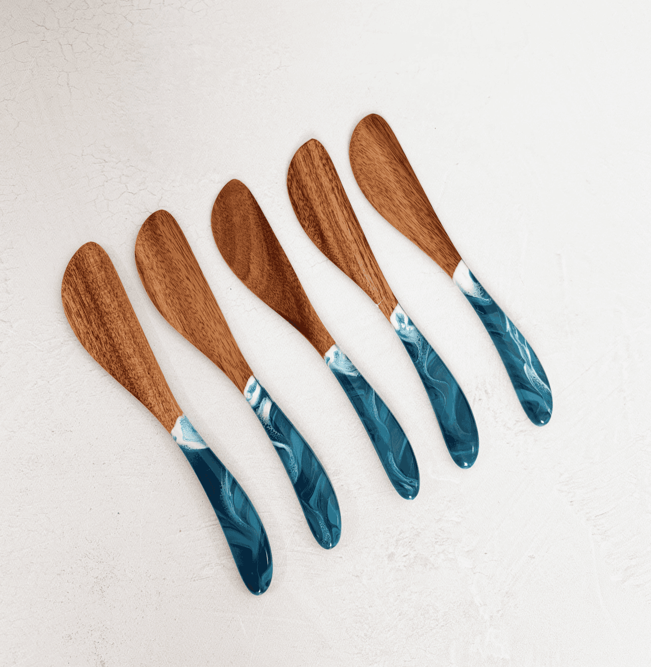 Set of five Lynn & Liana acacia cheese spreaders with teal Ocean Vibes resin handles arranged in a row