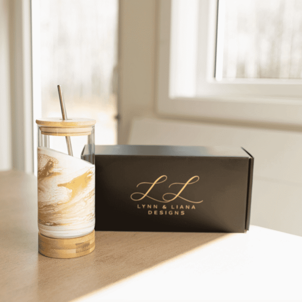 Gold Quartz resin glass tumbler by Lynn & Liana with bamboo lid, base and metal straw beside a Lynn & Liana Designs gift box