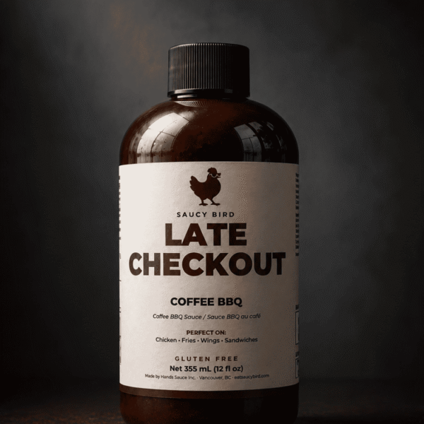 Bottle of Saucy Bird Late Checkout Coffee BBQ Sauce, 355 mL, on a dark grey background