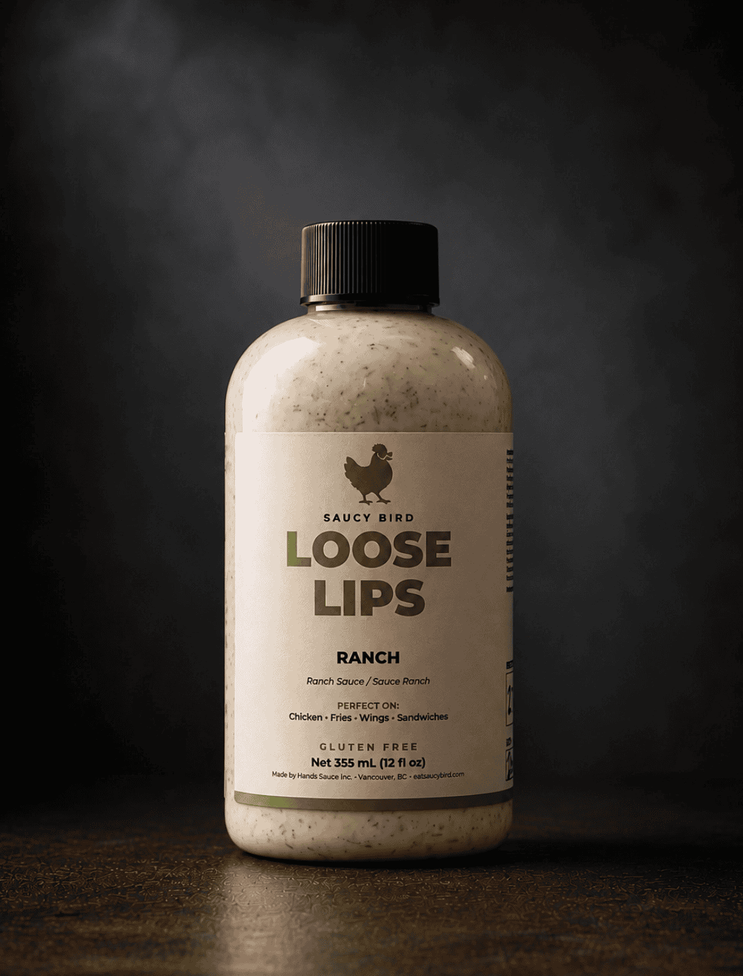 Bottle of Saucy Bird Loose Lips Ranch Sauce, a creamy speckled ranch, 355 mL, on a dark background