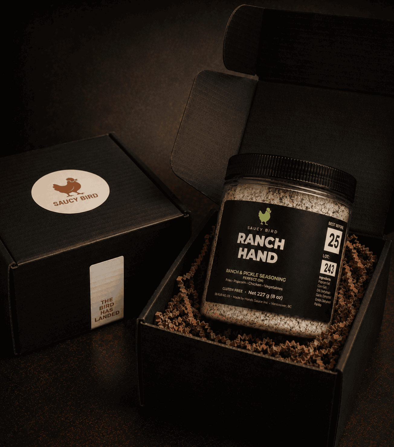 Jar of Saucy Bird Ranch Hand seasoning in an open black Saucy Bird gift box