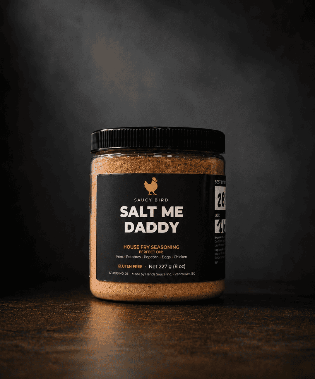 Jar of Saucy Bird Salt Me Daddy house fry seasoning, 227 g, on a dark background