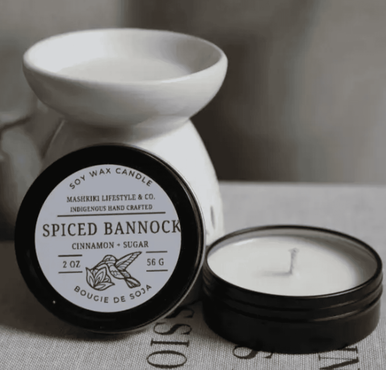 Mashkiki Spiced Bannock 2 oz soy wax candle tin in Cinnamon + Sugar, lid off beside a wax warmer