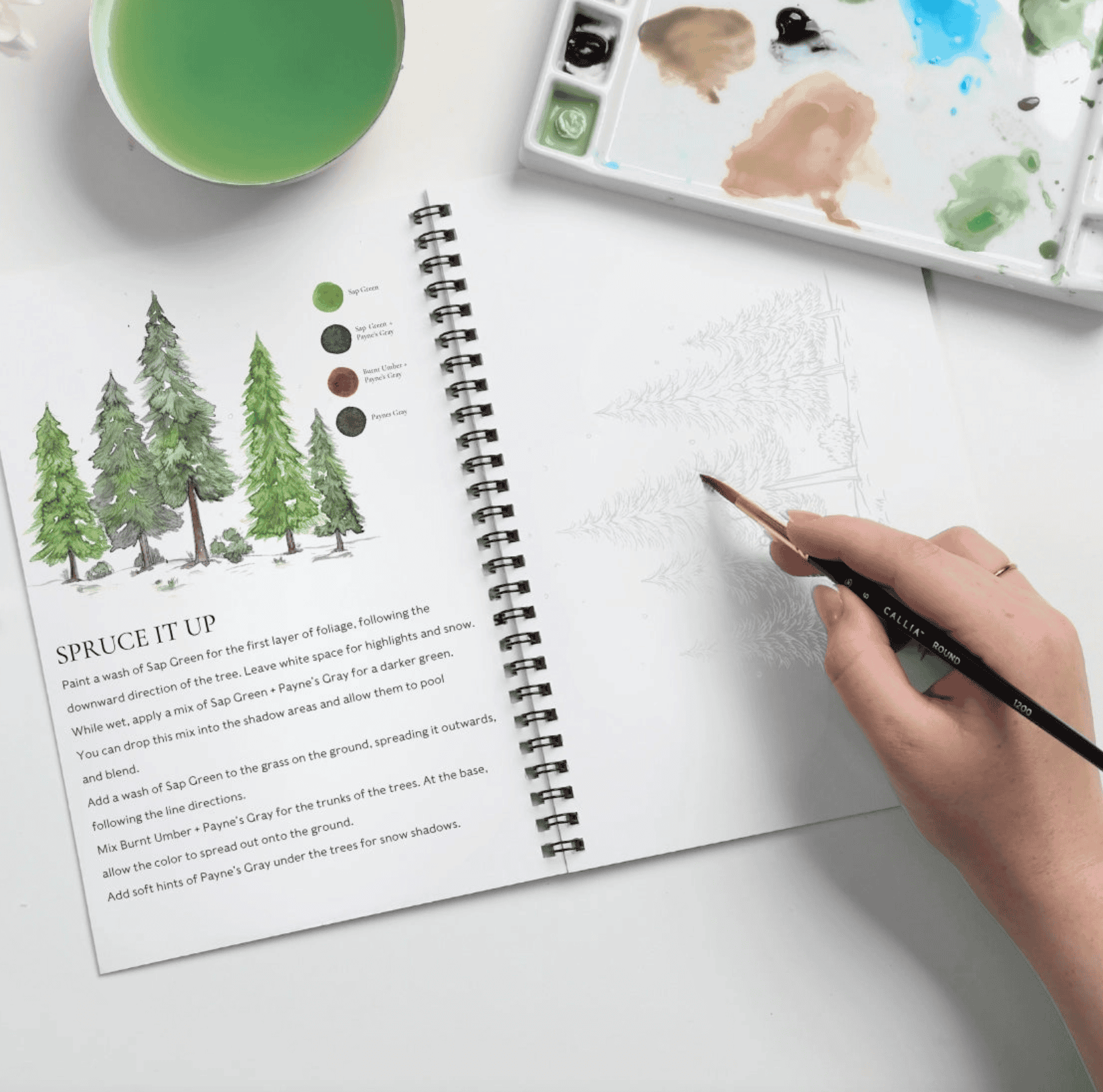 Winter Glow workbook open to the Spruce It Up project with a hand painting evergreen trees